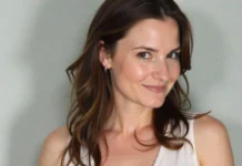 Portrait of actress Dylan Tays, known for her 1990s TV and music video roles, smiling against a neutral background.