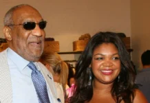 Evin Harrah Cosby attending a social event, standing beside a man in a light suit, with guests and woven baskets in the background.