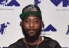 Karlous Miller smiling on stage, holding a microphone, representing Karlous Miller Net Worth and his success in comedy and entertainment.