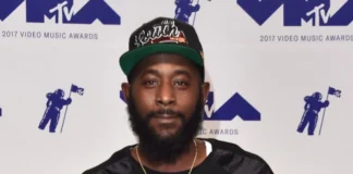 Karlous Miller smiling on stage, holding a microphone, representing Karlous Miller Net Worth and his success in comedy and entertainment.