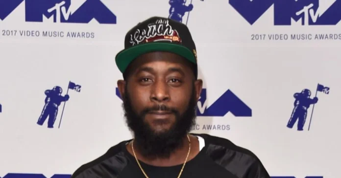 Karlous Miller smiling on stage, holding a microphone, representing Karlous Miller Net Worth and his success in comedy and entertainment.