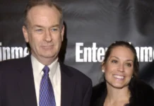 Maureen E. McPhilmy attends an Entertainment Weekly event, standing alongside a companion in formal attire before a branded backdrop.