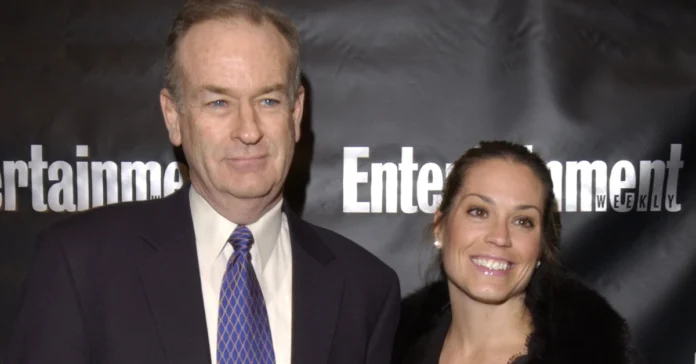 Maureen E. McPhilmy attends an Entertainment Weekly event, standing alongside a companion in formal attire before a branded backdrop.