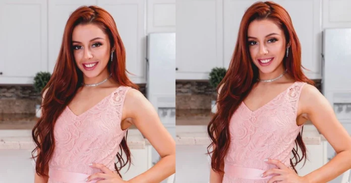 Vanna Bardeau smiling in a delicate pink lace dress with diamond jewelry, showcasing her signature red hair and elegant style in a modern kitchen setting