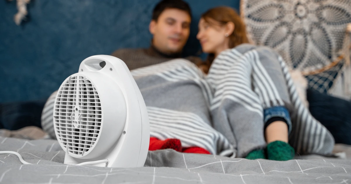 Couple relaxing in bed with white fan showing how cooling helps when body temperature naturally drops during sleep preparation