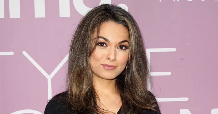 Aishah Hasnie, acclaimed Fox News correspondent, poses confidently at media event with stylish hair and professional appearance against pink backdrop