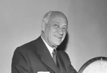 Conrad Nicholson Hilton smiling beside a globe, symbolizing his vision as the hotel magnate who built a worldwide hospitality empire