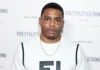 Nelly at a PrettyLittleThing event, wearing a white shirt and gold chain, representing his success and Nelly Net Worth.