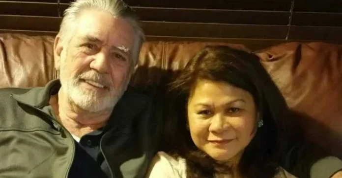 Nila Ermey sitting on a brown leather couch with her husband, sharing a quiet moment at home.