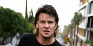 Alt Text: Theo Von looking intensely at camera with his signature mullet - the comedian whose net worth reflects his journey from MTV to podcasting millionaireRetryClaude can make mistakes. Please double-check responses.