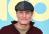 Woody Harrelson at premiere event wearing signature flat cap and burgundy hoodie, embodying the casual wellness-focused lifestyle of the Hollywood actor